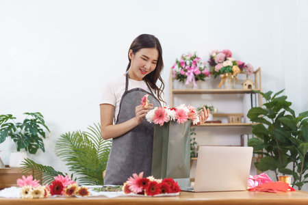 Florist concept, female florist making chrysanthemum and gerbera flower bouquet in shopping bag.の素材