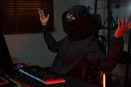 Hacker in hoodie raising hands while having problem with hacking programming system or server.の素材