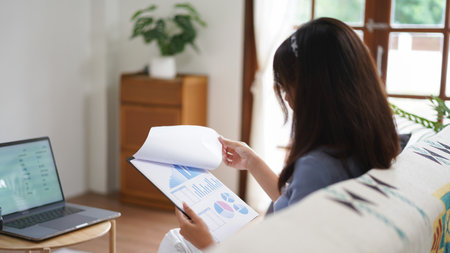 Work from home concept, Business women reading chart financial data while working remotely at home.の素材
