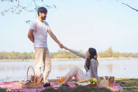 Young man holding rose bouquet behind his back to surprise girlfriend and holding hands together.の写真素材