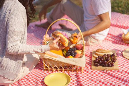 Young couple in love having breakfast together while sitting to picnic on blanket near lake in park.の写真素材