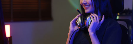 Female cyber hacker gamer in headphone around neck watching video games on monitor with having fun.の写真素材