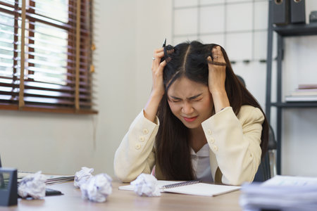 Secretary concept, Female secretary put hands on head while feeling stressed with mistake of work.の素材