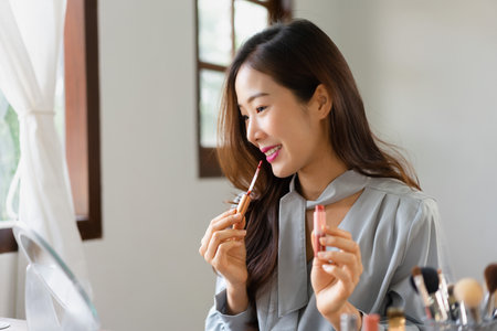 Beauty blogger applying lipstick on her mouth and reviewing cosmetics product in makeup vlogger.の写真素材
