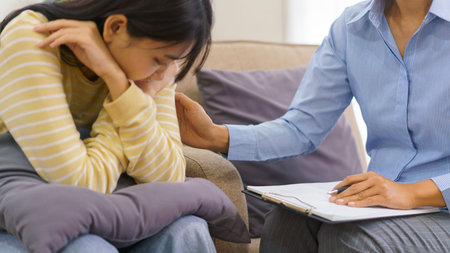 Female psychologist talking and comforting depressed patient while having session therapy in clinic.