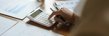 Businesswoman checking financial document of startup and calculate number with calculator in office.