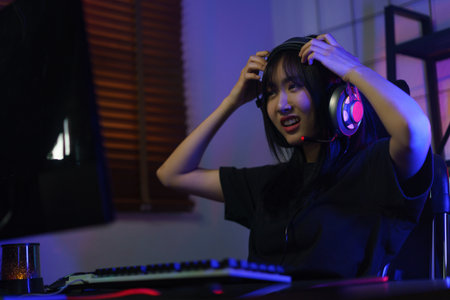 Female gamer in headphone confused while playing games or hacking programming system.の写真素材