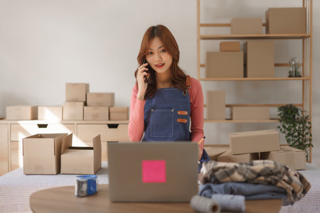Online business concept, Women entrepreneur talks with customer in phone and write data in notebook.の写真素材