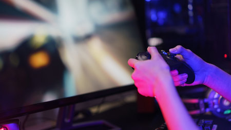 Hand of female gamer holding controller joystick to playing games on computer.