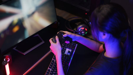 Female gamer playing or streaming video games on computer with joystick in neon light.の写真素材