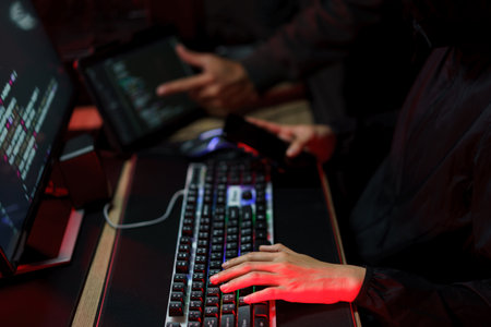 Hacker team using smartphone and typing code on keyboard to hacking programming system or server.の写真素材