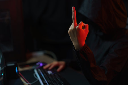 Hacker in hoodie showing middle finger and typing code to hacking programming system or server.の写真素材