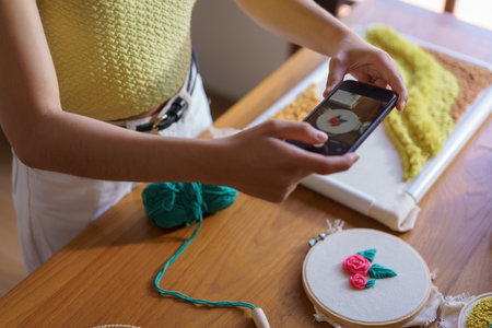 Hand embroidery concept, Women taking photo of embroidery fabric punch diy on canvas in wood hoop.の写真素材
