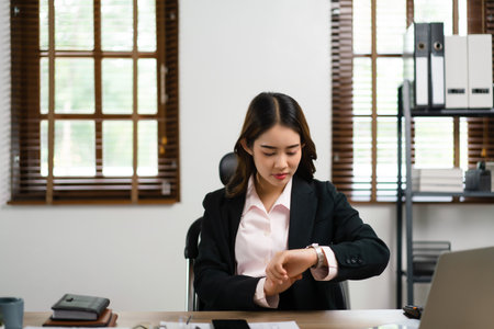 Businesswoman looking time on wrist watch while working about marketing plan of new startup project.の写真素材