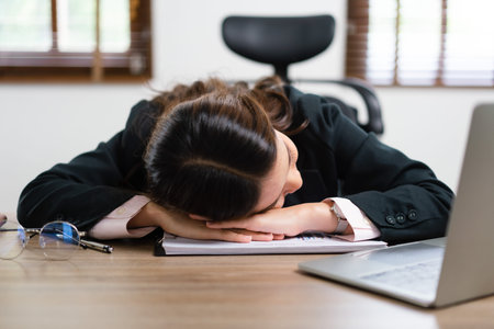 Businesswoman sleeping on her desk near laptop after exhausted from overworked in workplace.の写真素材