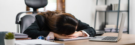 Businesswoman sleeping on her desk near laptop after exhausted from overworked in workplace.