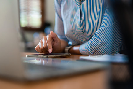 Close up hands of businessman use smartphone to searching business data or chatting with colleague.の写真素材