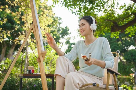 Artist concept, Female artist holding brush and painting picture on canvas while listening music.の写真素材