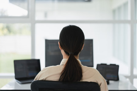 Back of developer programmer working on multiple monitor to programming code and developing website.