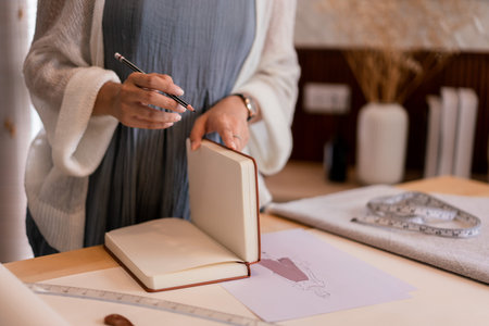 Asian tailor women creative and designing new fashion collection while drawing sketch in notebook.の写真素材