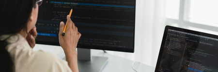 Developer programmer holds pencil and checking code on monitor while programming to developing web.