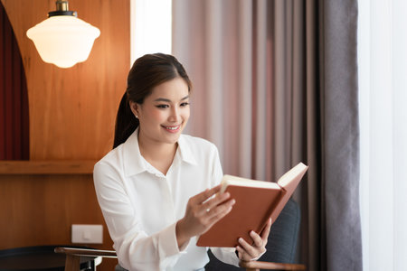 Businesswoman reading a book to relaxation after working about business project in home office.の写真素材