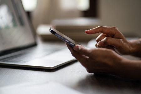 Female entrepreneur researching data on smartphone and working on laptop about new startup project.
