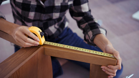 Women measuring length of chair with measure tape while assembling and renovation chair furniture.の写真素材