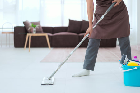 Maid using mop with bucket plastic of cleaner equipment to mopping cleanup floor in living room.の写真素材