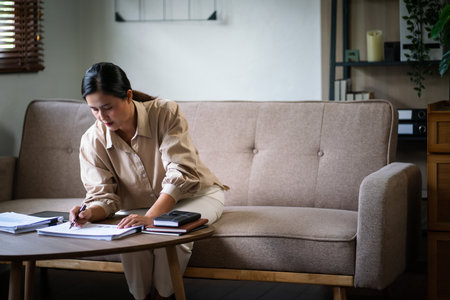 Female entrepreneur working to reading document and writing notes while analysis finance of startup.の写真素材