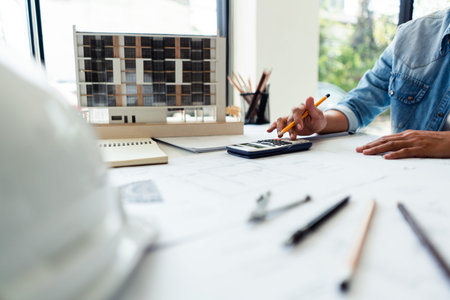 Engineer woman use scientific calculator and working to drawing construction on blueprint in office.