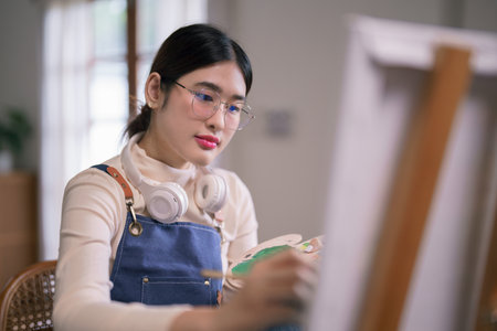 Young asian female artist use paintbrush and color to drawing and painting create artwork on canvas.の写真素材
