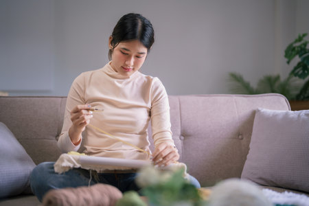 Young asian woman use punch needle and yarn to embroidery craft on fabric frame in hobby lifestyle.の写真素材