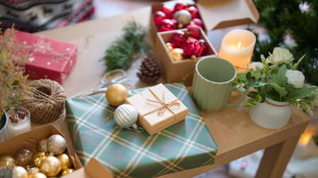 Christmas present with ball baubles and xmas ornaments on the wooden table near christmas tree while preparing decoration for celebration christmas festive holiday and winter seasons at home.の写真素材