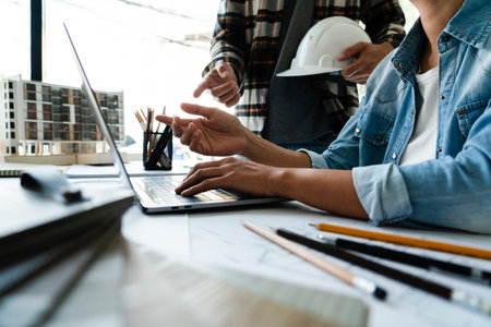 Female engineer explains about blueprint of construction on laptop while brainstorming with partner.の写真素材