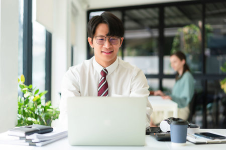 Businessman working to typing finance data of business on laptop in modern workplace with colleague.の写真素材