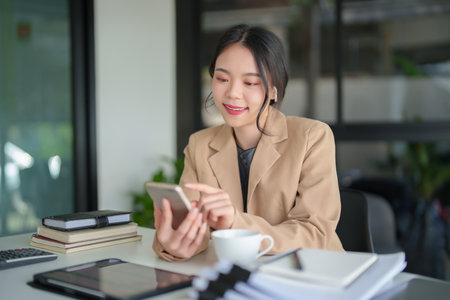Businesswomen wearing bluetooth headphones and using smartphone to meeting on video call about financial and investment data of new business while discussion management about new startup project.の写真素材