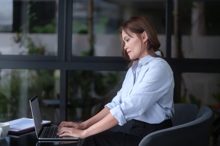Asian businesswomen typing business information on keyboard laptop to working about planning of marketing business report while analyze investment and market stock of new startup in outside workplace.の写真素材