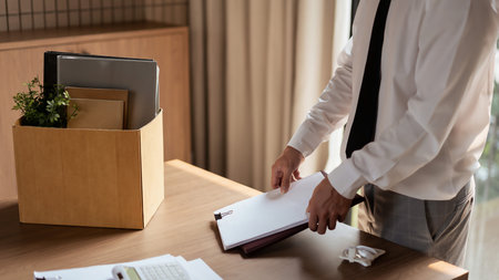 Male employee packing document and belongings in brown cardboard box after sends resignation letter.の写真素材