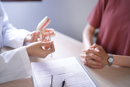 Asian dentist doctor women holding model of human jaws with teeth explaining about oral dental treatments to female patient while examination teeth and discussion about dental health in dental clinic.の写真素材