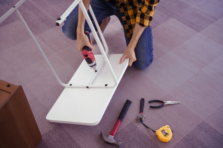 Women use electric screwdriver to installation screw and assembling table furniture for new house.の写真素材