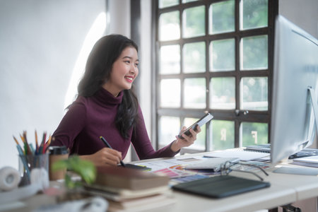 Graphic designer freelance women thinking creative ideas and using digital tablet to sketching logo brand while working to designing about graphic design with technology equipment in home studio.の写真素材