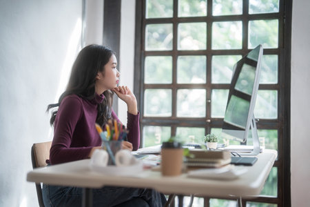 Graphic designer freelance women thinking creative ideas and using digital tablet to sketching logo brand while working to designing about graphic design with technology equipment in home studio.の写真素材