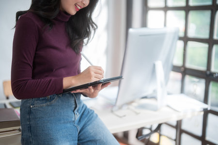 Graphic designer freelance women thinking creative ideas and using digital tablet to sketching logo brand while working to designing about graphic design with technology equipment in home studio.の写真素材