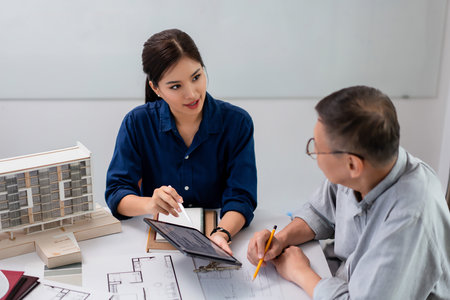 Two architects checking blueprint on tablet to planning about construction of building project.の写真素材