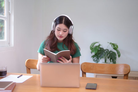 Young asian student women wearing headphone to studying and watching lecture webinar in online class...