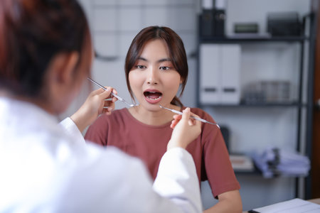 Asian dentist doctor women using explorer mirror tool to examining teeth of patient and explaining about oral dental treatments while discussion about dental health and healthcare in dental clinic.の写真素材