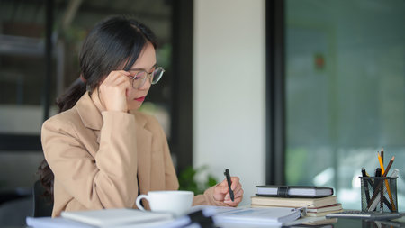 Businesswomen wear glasses to reading business report and checking finance chart data for thinking...