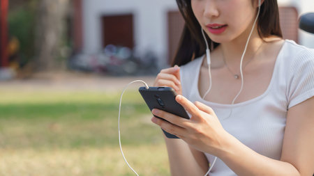 Closeup of young asian women wearing earphone to listening audio music and watching entertainment on...