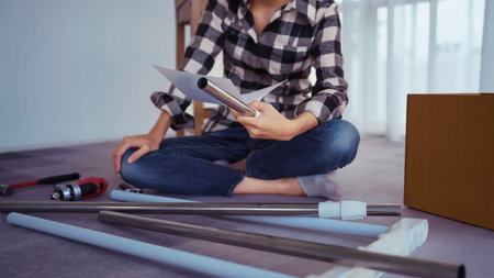 Women reading installation manual and instructions document while assembling furniture at home.の写真素材